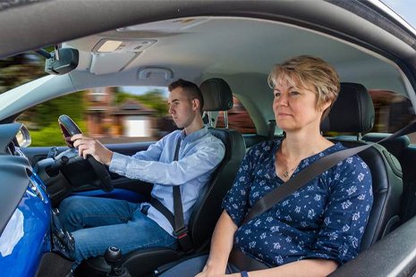 Female driving instructor with young male learner at the wheel